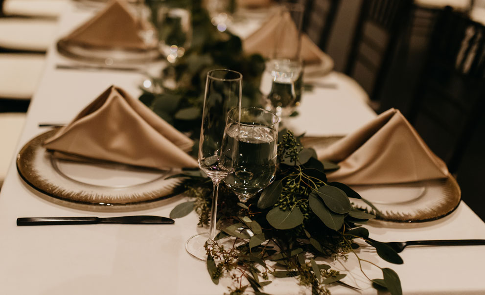 Elegant wedding table setting with greenery and glassware catered by Green Mangos Catering in the Twin Cities,